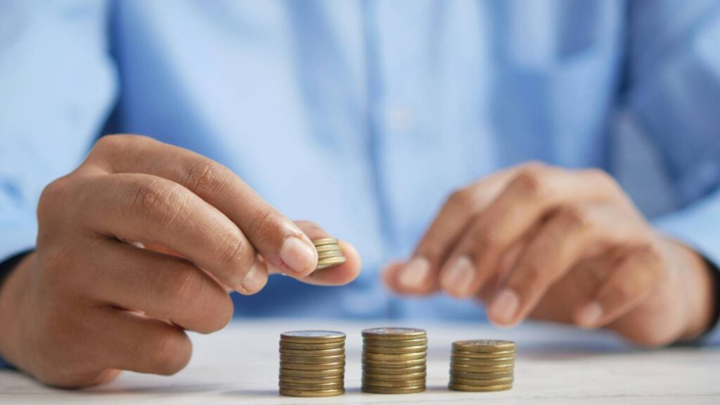 A photo of a man making several stacks of coins