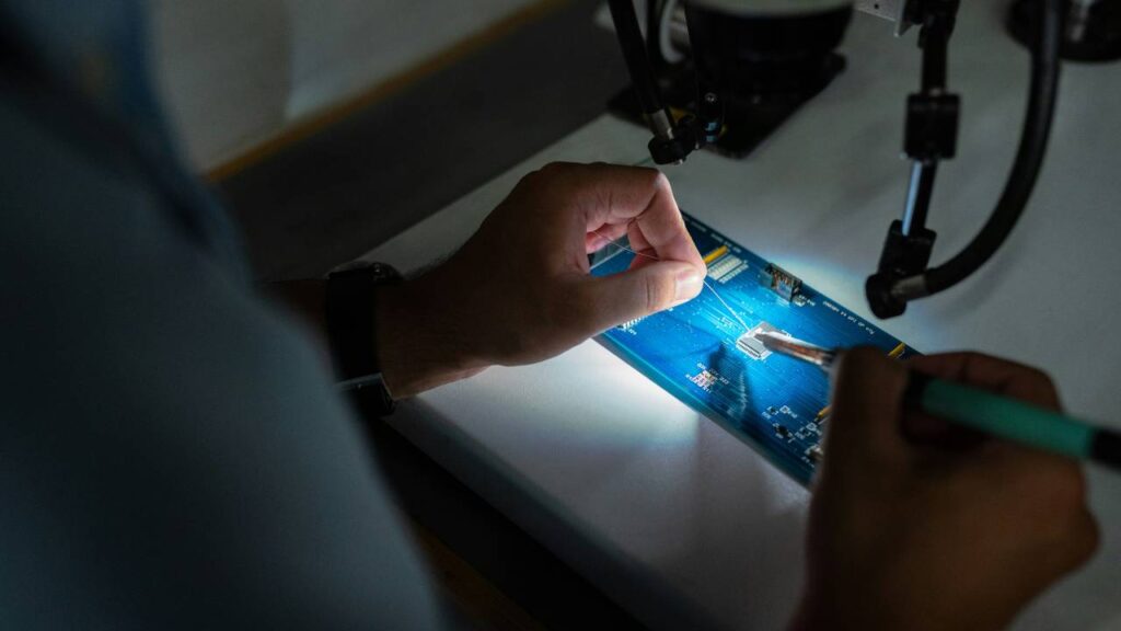 A photo of a man repairing a motherboard chip