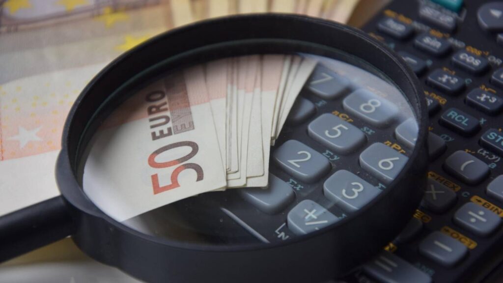 Euro bills, a calculator, and a magnifying glass